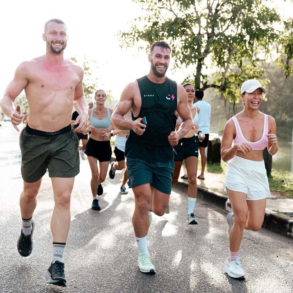 A photorealistic image of a person using a laptop in a comfortable home setting, following a fitness tutorial on screen. Focus on the screen displaying a clear, easy-to-follow exercise routine. The lighting should be warm and inviting. The camera angle is a medium shot, capturing the person from the side. The expression should be one of focus and determination. Props include yoga mat and water bottle.